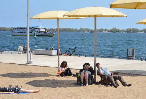 sitting under yellow beach umbrellas beside Lake Ontario