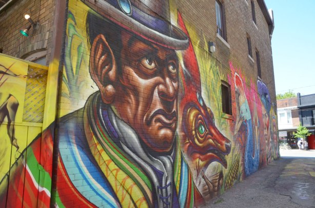 part of a large mural - a man wearing a bowler hat and a striped jacket, seen from the shoulders up.