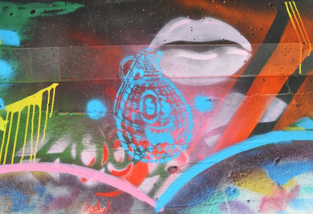 street art under a railway underpass - pink lips and a blue bomb with a smiling face on it  by spud