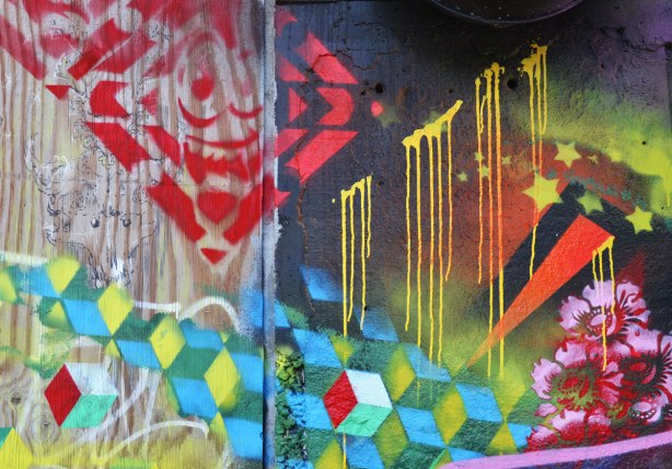 street art under a railway underpass - yellow stars, 3 D blocks and some pink flowers