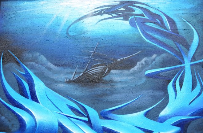 blue street art painting of a wrecked sailing ship partially submerged as she sinks stern first