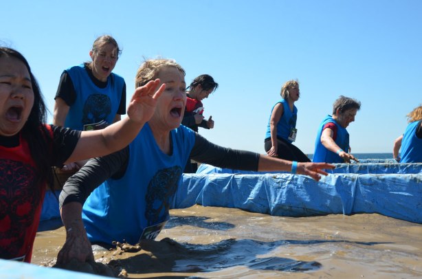 a group of people are wading through deep muddy cold water and they don't look happy about it