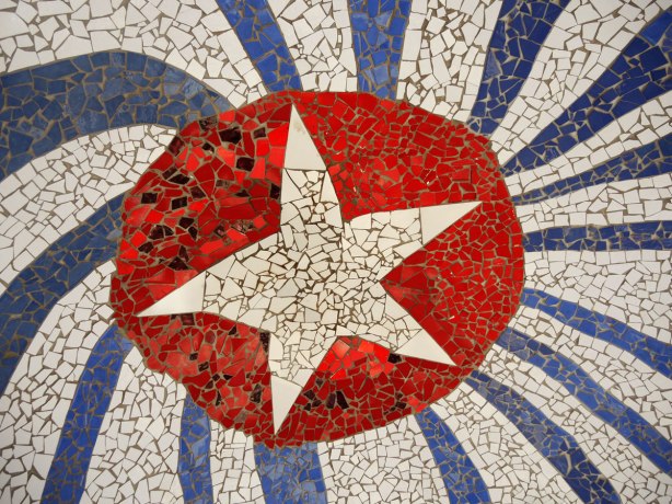 part of a large mosaic installation, ceramic tile pieces, white star in red circle surrounded by blue and white rays radiating from the center to look like the cuban flag