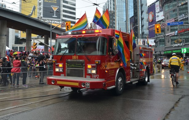 Toronto fire truck in pride parade, rainbow flags decorate the fire truck