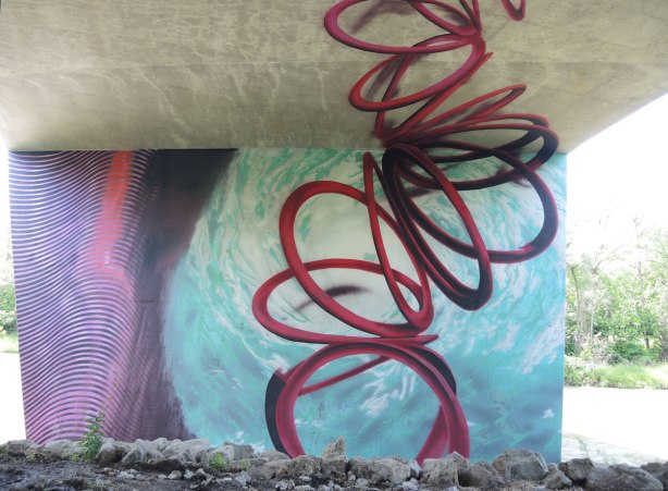 Mural of swirling water and a tangled spiral shape in red representing a hurrican rising from the eye of the storm upwards to the underside of the road 