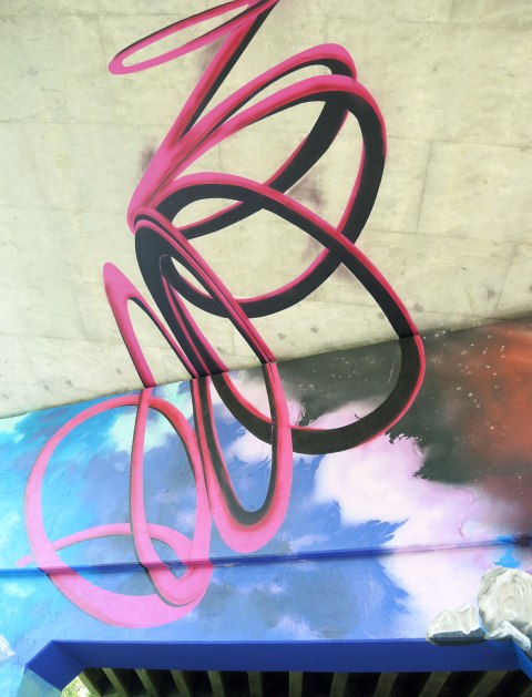 part of a mural under a bridge -  a tangled spiral shape in red representing a hurrican rising from the eye of the storm upwards to the underside of the road 