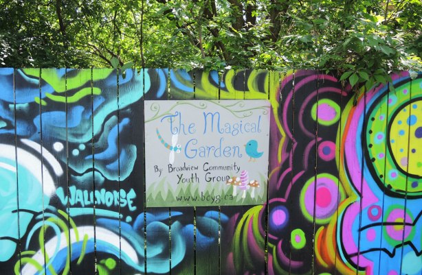 sign on a painted fence in a park that says 'The Magical Garden by Broadview Community Youth Group'