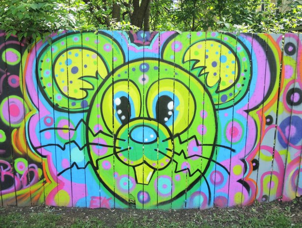 street art painting of a bright green and yellow mouse head 