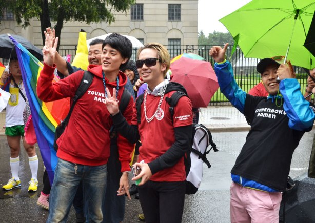 Three young men making peace signs as they pose for a camera 