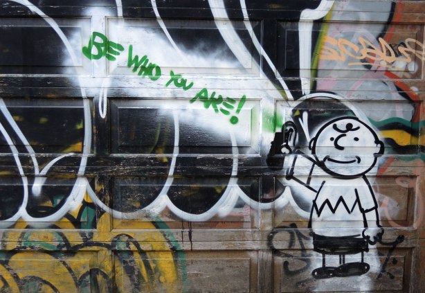 graffiti and street art in Graffiti Alley in Toronto - Charlie Brown in the bottom right corner of a garage.  In green are the words Be WHo You Are