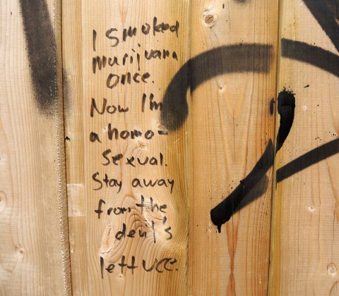 graffiti and street art in Graffiti Alley in Toronto - on a wood fence, someone was scrawled the words 