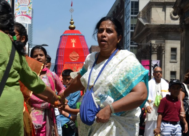 people are using a long thick rope to pull a float down a city street for a parade.