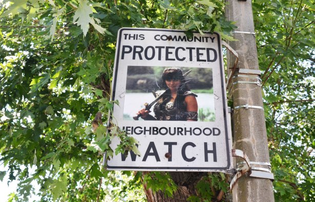 An altered Neighbourhood Watch sign. A woman. Xena the warrior princess character.