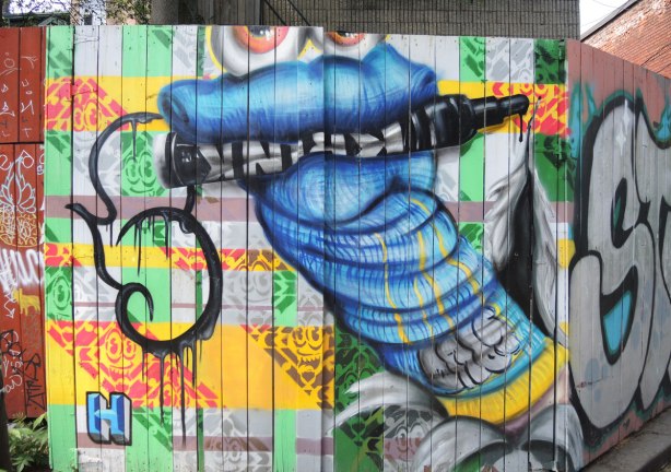 graffiti and street art in Graffiti Alley in Toronto - a large blue socket puppet with bulging eyes and a big black marker in its mouth. 