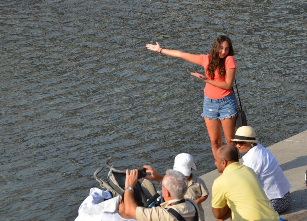 A young woman gestures towards the Toronto sign (which is not in the photograph). 