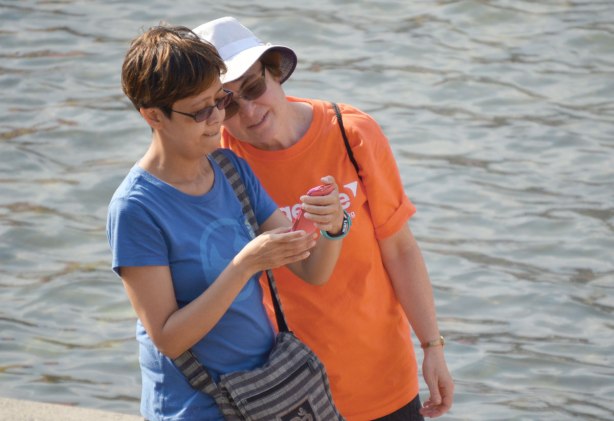 Two women check a picture on a smartphone.  They have just taken a selfie. 