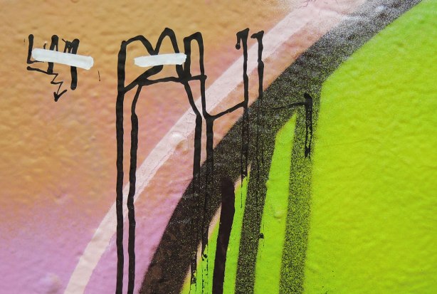 close up of a street art painting that now looks abstract, black lines on green, pink and beige 