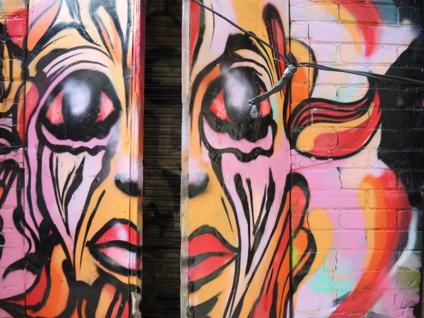 double doors painted in a pink, orange and red face (large face), the doors are slightly open so there is now a gap down the middle of the nose and mouth