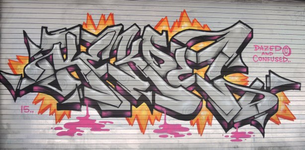 tag in silver and black with pink and orange highlights on a grey metal door 