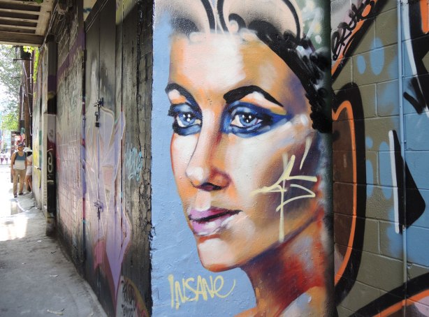 woman's face in profile painted on a wall in an alley