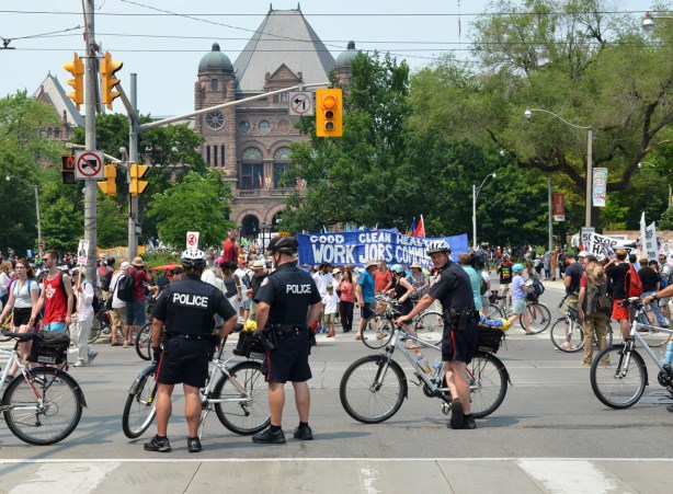 policemen on bikes block the street as they direct a march through city streets