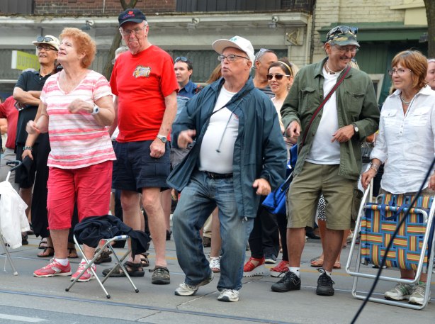 a group of older people dancing to the music on the street at a street music festival