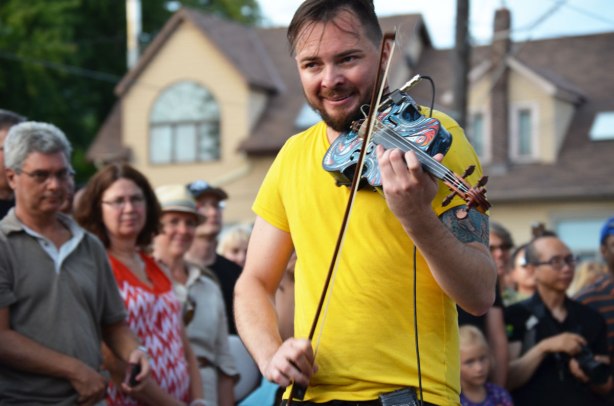 Dr. Draw playing his violin in front of a crowd, outdoor street music festival