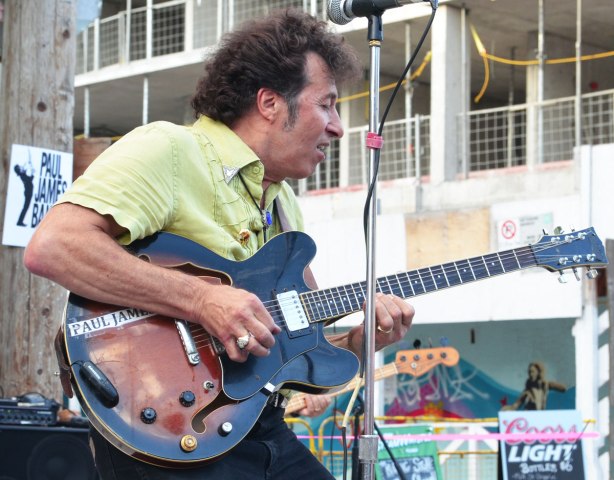 man playing the guitar outdoors at a street music festival