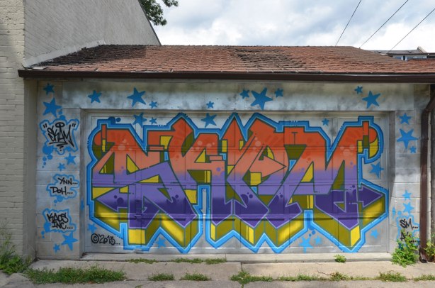 tag like street art on a garage door in an alley  ynn doh