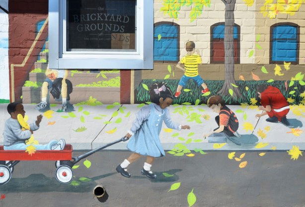 part of mural that depicts a street scene - a little girl pulls a boy in a red wagon while other kids are playing on the sidewalk