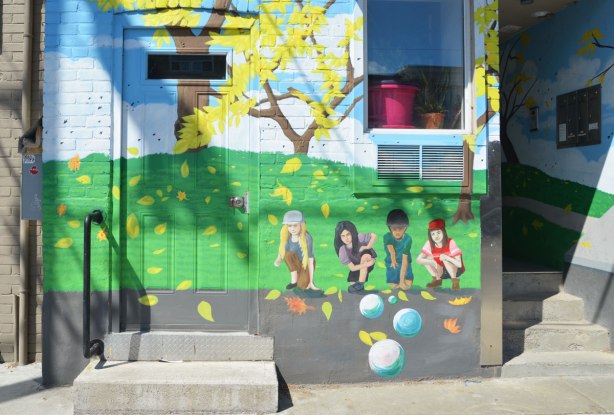 part of mural that depicts a street scene - four kids are playing marbles 