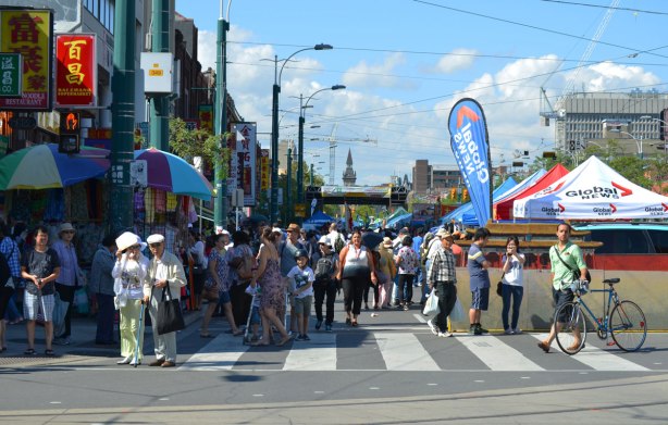 looking north from Dundas, up Spadina. Part of the street is closed to traffic to make room for the Chinatown festival. Many people are waiting at the red light. 