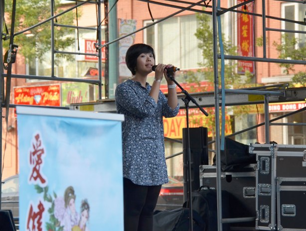 A chinese woman sings on an outdoor stage at the Chinatown festival on Spadina Ave
