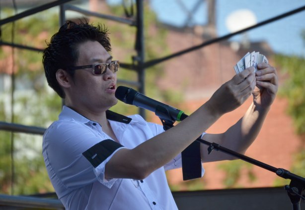 magician Stephen Cheung shows a deck of cards at an outdoor show