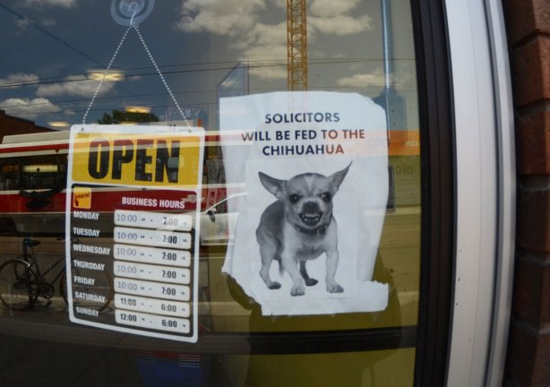 sign on the door of a store that says Solicitors will be fed to the chihuahua, with a picture of a little chihuahua dog below the words