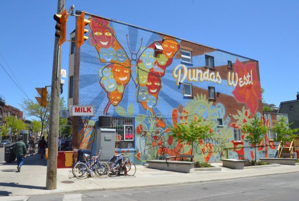 building on the corner of Sheridan and Dundas is a two storey brick building. On the whole of the side wall is a large Dundas West mural featuring a large butterfly painted on it. 