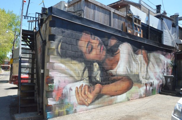 a Jarus street art painting of a woman sleeping on a bed. She has long black hair and is wearing white clothes