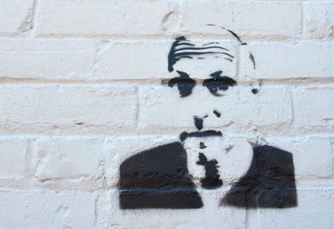 black stencil of a man's head on a white brick wall