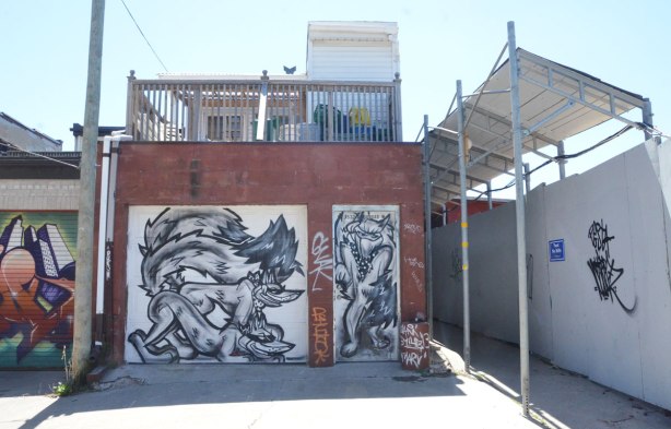 garage door with three black line drawn foxes, there is a construction site to the right of the garage