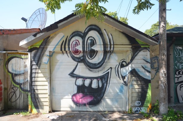 A large white spud character on a garage door, with big googly eyes and arms that come out from where his ears are