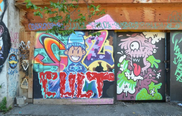 a number of colourful street art paintings on a garage door and gate in an alley