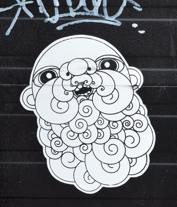 Black and white wheatpaste of a man's head, bald but with a large curly beard. Line drawing