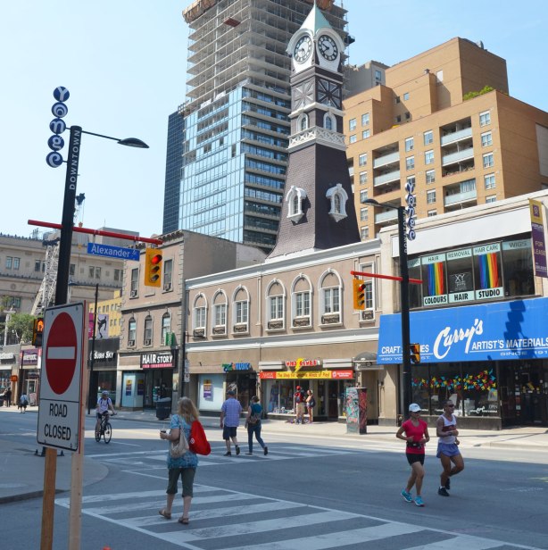 Two women are jogging, and other people are walking, on Yonge street on a Sunday morning at Open Streets Toronto so there is no traffic.