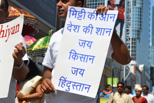 A man is holding up a sign with words written in Hindi