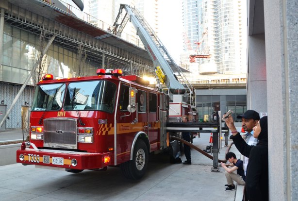 A woman in a head scarf is taking a selfie while she stands with some other people by a firetruck. 