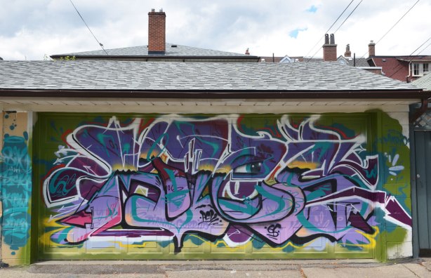 tag like street art on a garage door in an alley Diana Gordito