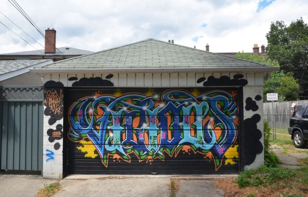 tag like street art on a garage door in an alley