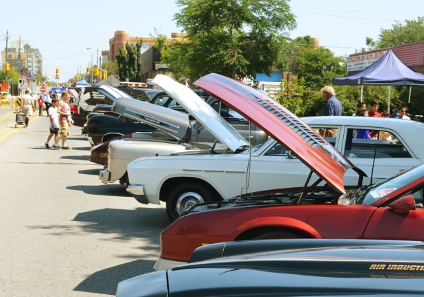 picture taken at a car show - a line of cars on display with their front hoods up