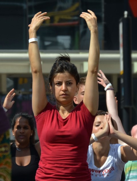 men and women at a yogathon - doing yoga outside in a large group