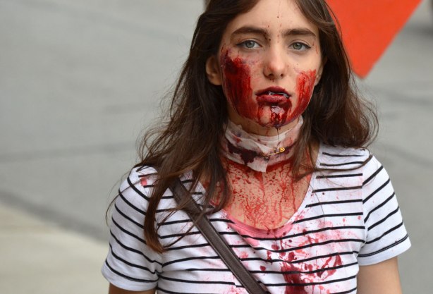 people dressed up as zombies - a young woman with dead looking empty eyes and blood dripping from her mouth 